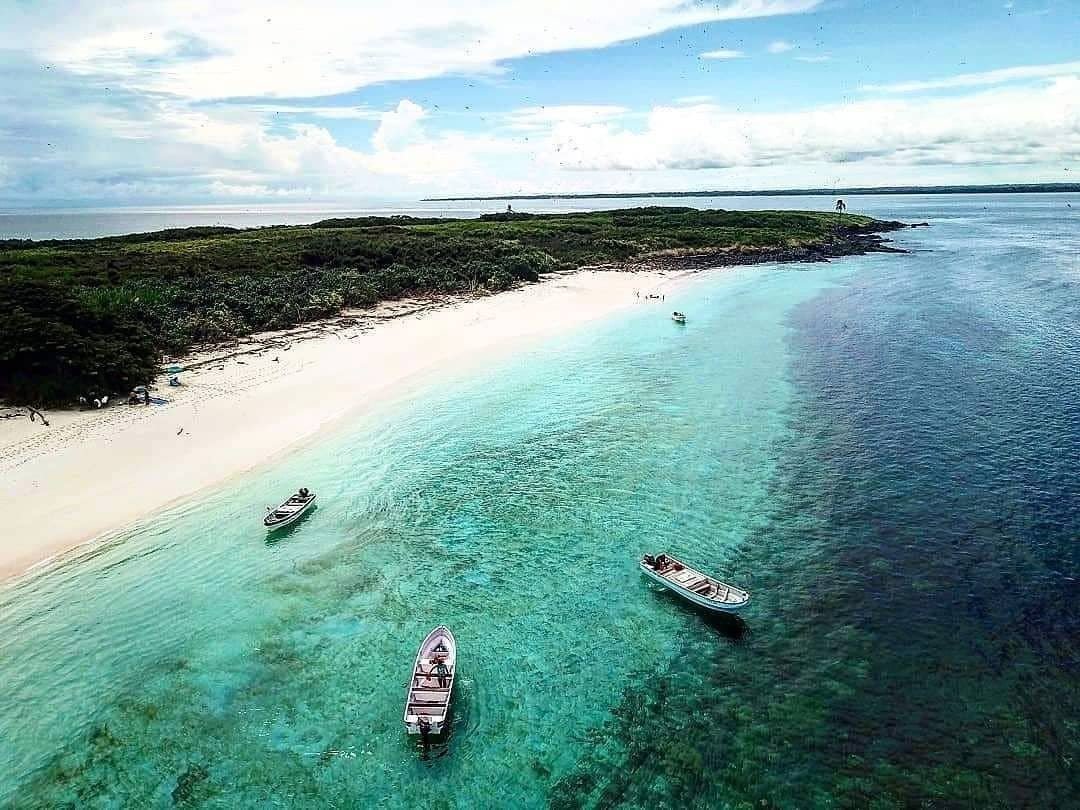 Boats off a white sand beach with turquoise water